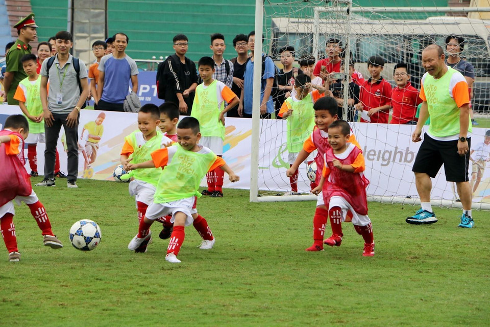 HLV Park Hang Seo vui vẻ chơi bóng cùng các em học sinh. (Ảnh: Trung Kiên/TTXVN)