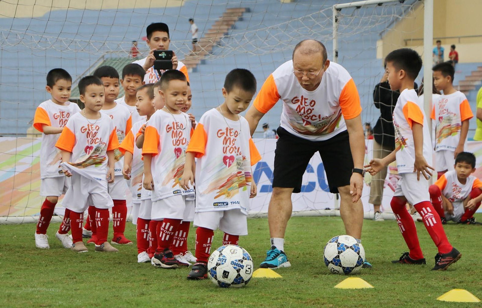 HLV Park Hang Seo hướng dẫn các em học sinh khởi động trước khi chơi bóng đá. (Ảnh: Trung Kiên/TTXVN)