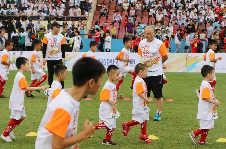 HLV Park Hang Seo hướng dẫn các em học sinh khởi động trước khi chơi bóng đá. (Ảnh: Trung Kiên/TTXVN)