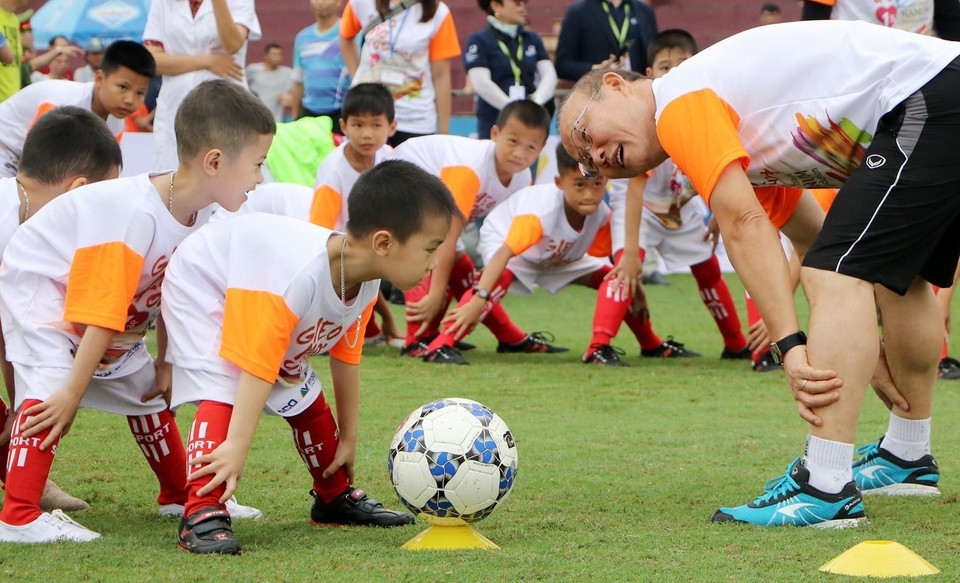 HLV Park Hang Seo hướng dẫn các em học sinh khởi động trước khi chơi bóng đá. (Ảnh: Trung Kiên/TTXVN)