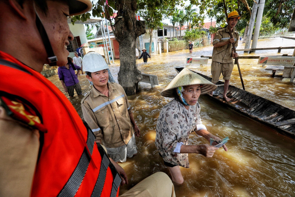 Công an huyện Lệ Thủy cùng các tổ chức thiện nguyện đến cứu trợ tiền và gạo cho người dân thôn Phú Thọ, xã An Thủy. (Ảnh: Thành Đạt/TTXVN)