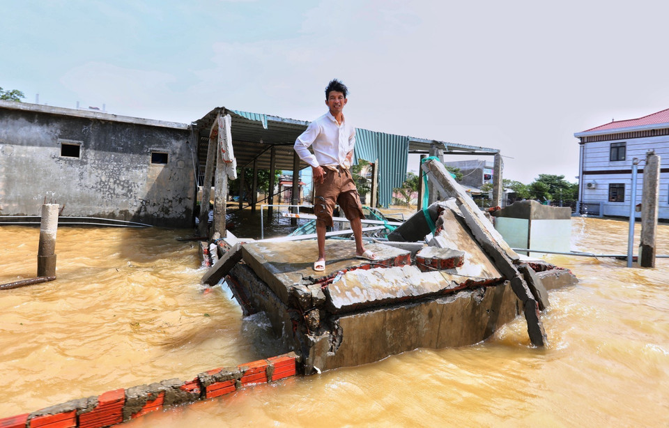 Người đàn ông này ngậm ngùi đứng trên ngôi nhà đã sập gần như hoàn toàn sau trận lũ dữ lịch sử. (Ảnh: Thành Đạt/TTXVN)