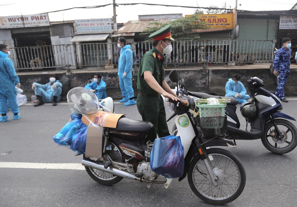 Lực lượng kiểm soát quân sự vận chuyển xe máy cho người dân lên xe ôtô chở về quê. (Ảnh: TTXVN phát)