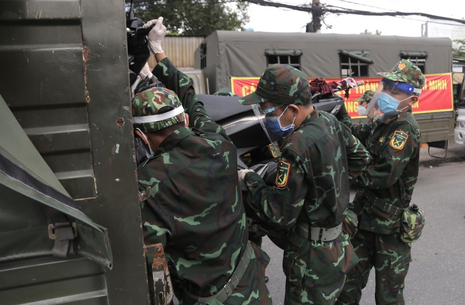 Lực lượng quân đội hỗ trợ vận chuyển xe máy cho người dân lên xe ôtô chở về quê. (Ảnh: TTXVN phát)