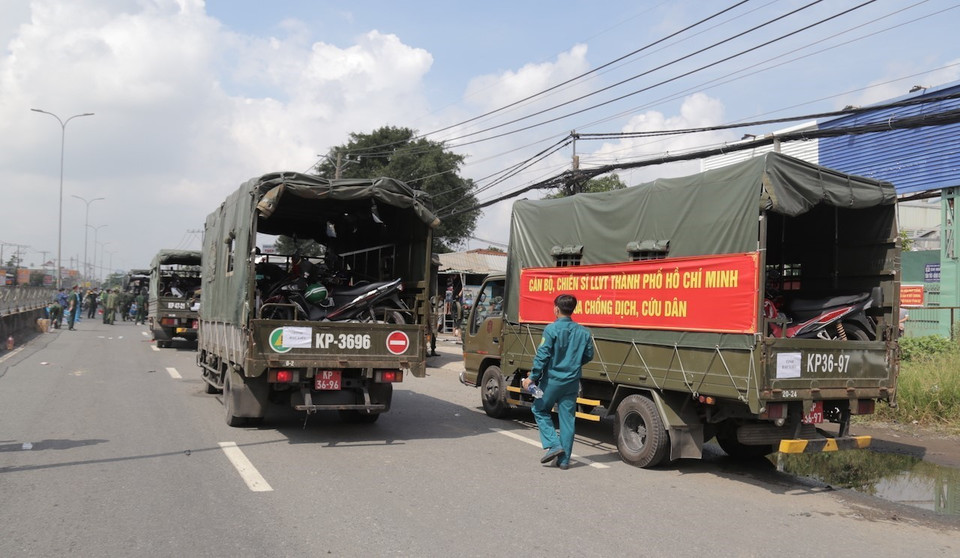 Lực lượng kiểm soát quân sự vận chuyển xe máy cho người dân lên xe ôtô chở về quê. (Ảnh: TTXVN phát)