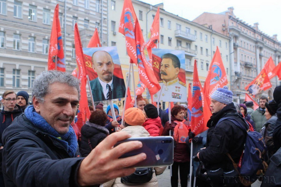 Người dân Moskva (Liên bang Nga) ghi lại hình ảnh đoàn người diễu hành qua các tuyến phố nhân kỷ niệm lần thứ 102 Cách mạng Tháng Mười vĩ đại (2019). (Ảnh: Trần Hiếu/TTXVN)