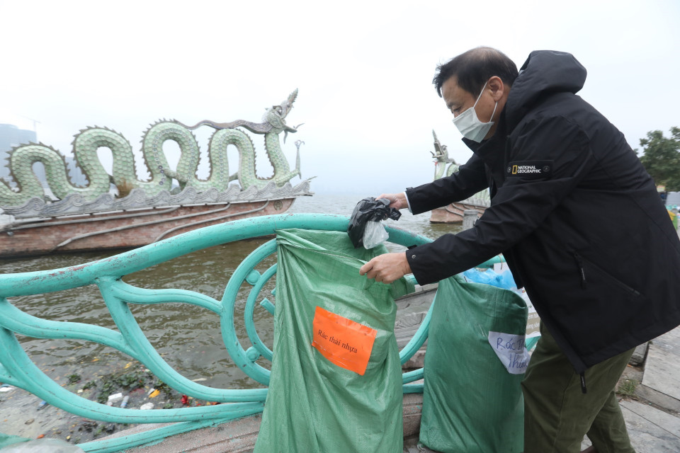 Người dân cho túi nilon vào nơi quy định sau khi thả cá xuống hồ. (Ảnh: Minh Quyết/TTXVN)