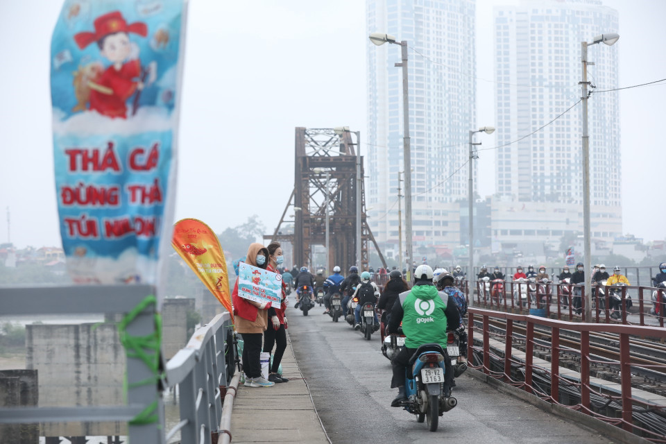 Tại khu vực cầu Long Biên, các tình nguyện viên tham gia hỗ trợ người dân thả cá, gom rác để xử lý. (Ảnh: Minh Quyết/TTXVN)