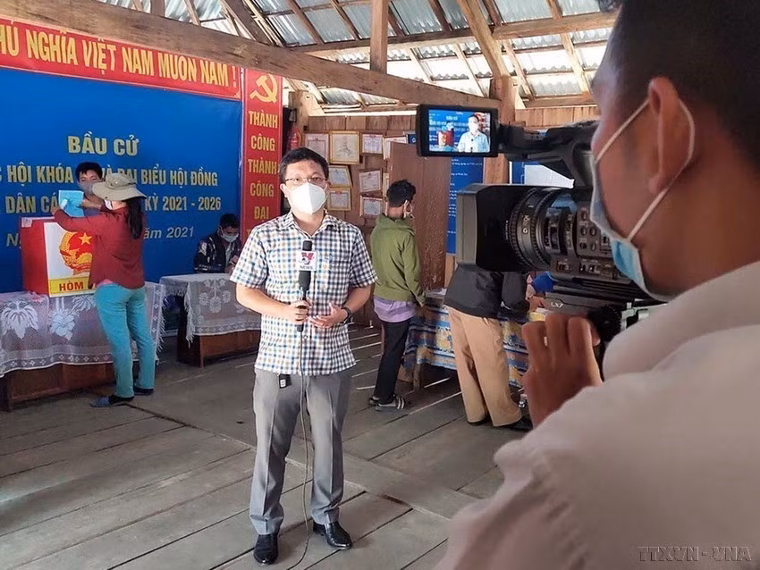 Trưởng cơ quan thường trú TTXVN tại tỉnh Kon Tum Hoàng Cao Nguyên và phóng viên Khoa Chương đưa tin bầu cử sớm tại điểm bầu cử số 3, thôn Măng Khênh, xã Đăk Man, huyện Đăk Glei, tỉnh Kon Tum (2021). (Nguồn: TTXVN)
