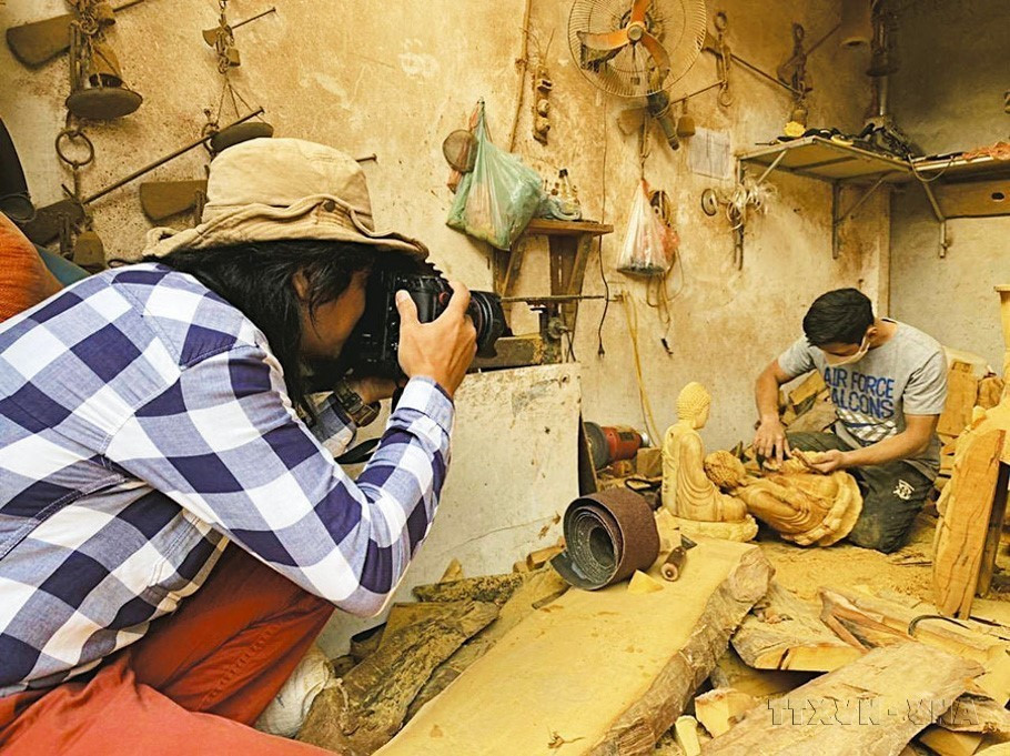 Phóng viên An Thành Đạt, Báo ảnh Dân tộc và Miền núi (TTXVN) tác nghiệp tại làng nghề Sơn Đồng, Hoài Đức, Hà Nội, tháng 12/2022. Nguồn: TTXVN)