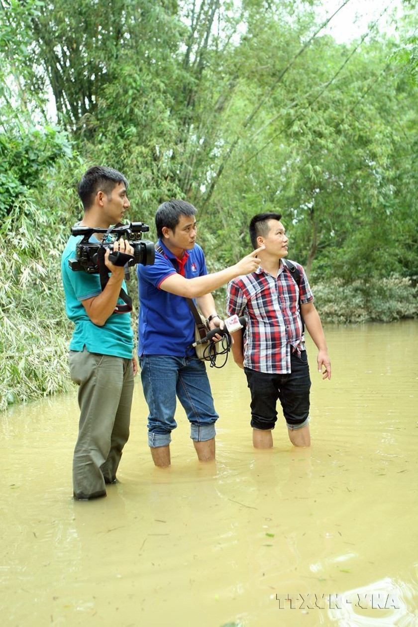 Phóng viên Trung tâm Truyền hình thông tấn tác nghiệp tại tâm lũ Hương Khê, Hà Tĩnh (10/2016). (Nguồn: TTXVN)