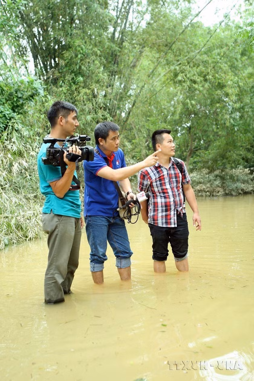 Phóng viên Trung tâm Truyền hình thông tấn tác nghiệp tại tâm lũ Hương Khê, Hà Tĩnh (10/2016). (Nguồn: TTXVN)