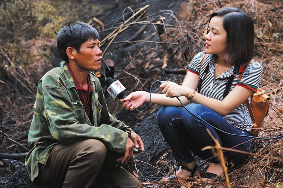 Phóng viên Hoàng Ngà, Cơ quan Thường trú TTXVN tại Hà Tĩnh, phỏng vấn cựu chiến binh Đậu Văn Tiến - người tham gia mở đường băng cản lửa tại hiện trường vụ cháy rừng ở huyện Nghi Xuân, Hà Tĩnh, tháng 7/2019. (Nguồn: TTXVN)