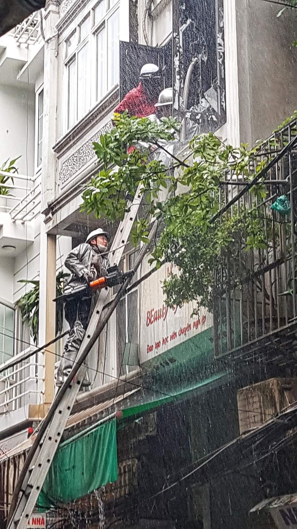 Lực lượng chức năng phải phá cửa để đưa vòi nước vào trong nhà dập lửa. (Ảnh: Tuấn Anh/TTXVN)