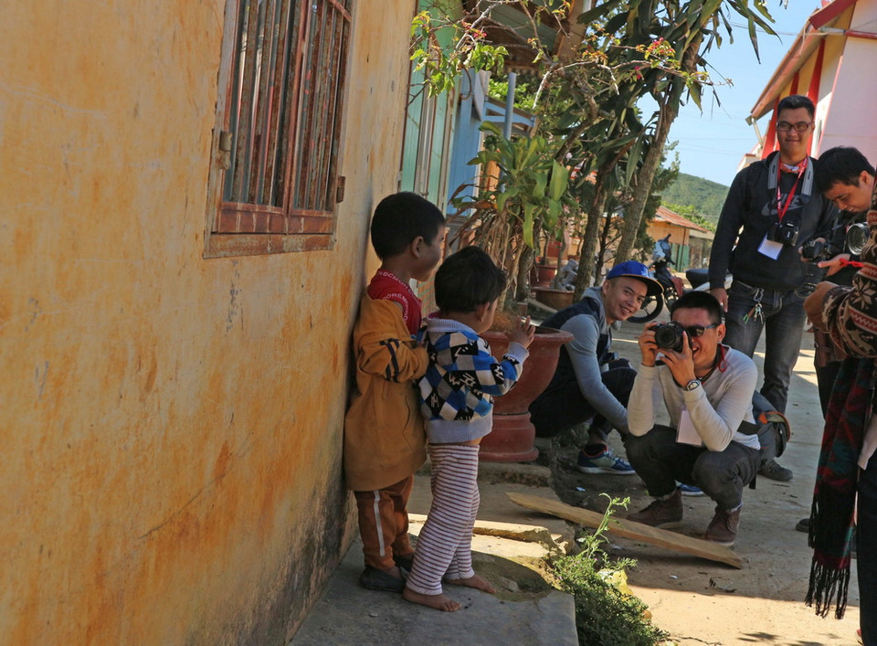 Một nhóm du khách trẻ chụp hình các em nhỏ trong buôn làng. (Ảnh: Nguyễn Dũng/TTXVN)