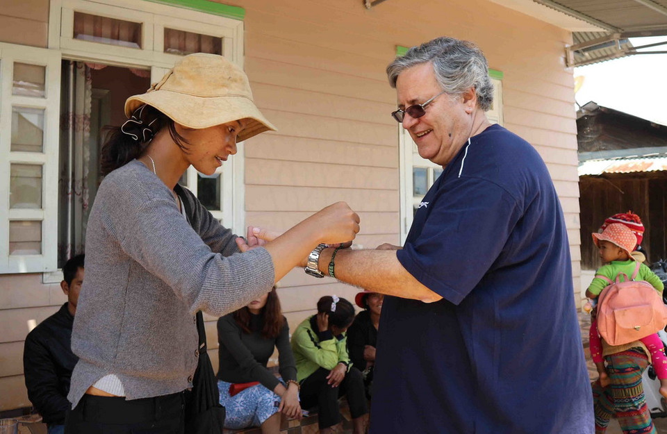 Chị Rolan Cơ Liêng tặng vị khách người nước ngoài một vòng đeo tay dệt bằng thổ cẩm đặc trưng của dân tộc mình. (Ảnh: Nguyễn Dũng/TTXVN)