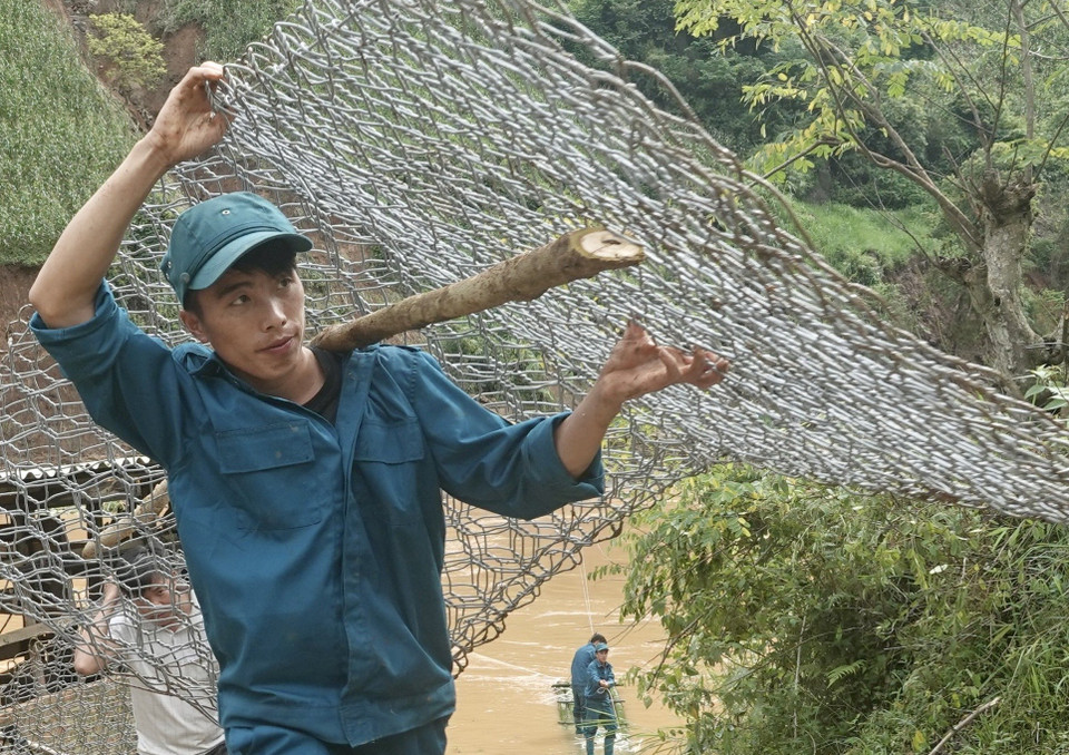 Lực lượng dân quân vận chuyển rọ đá đi khắc phục các tuyến đường bị hư hỏng tại bản Đề Sủa, xã Lao Chải Hồ. (Ảnh: Tuấn Anh/TTXVN)