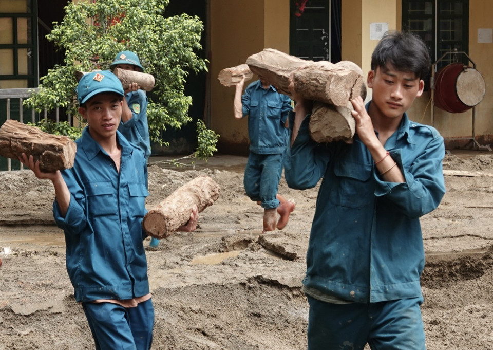 Lực lượng dân quân tham gia khắc phục bão lũ tại trường Phổ Thông dân tộc bán trú Tiểu học và Trung học Cơ sở xã Hồ Bốn. (Ảnh: Tuấn Anh/TTXVN)