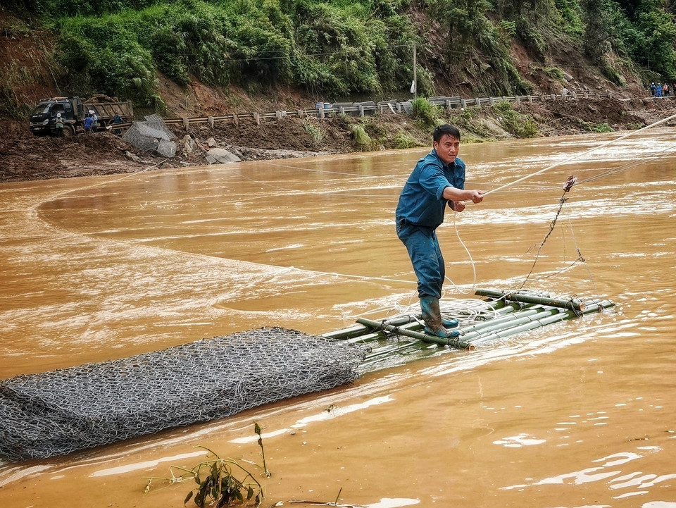 Dân quân dùng bè mảng vận chuyển rọ đá đi khắc phục các tuyến đường bị hư hỏng tại bản Đề Sủa xã Lao Chải Hồ. (Ảnh: Tuấn Anh/TTXVN)