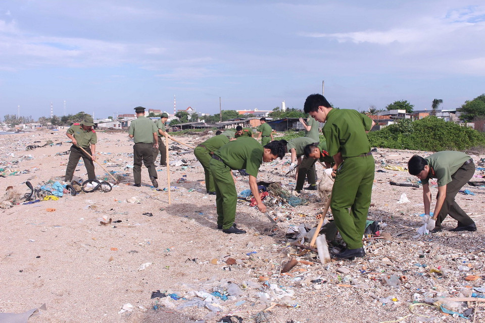 Lực lượng thanh niên công an tham gia thu gom rác thải dọc bãi biển. (Ảnh: Hồng Hiếu/TTXVN)