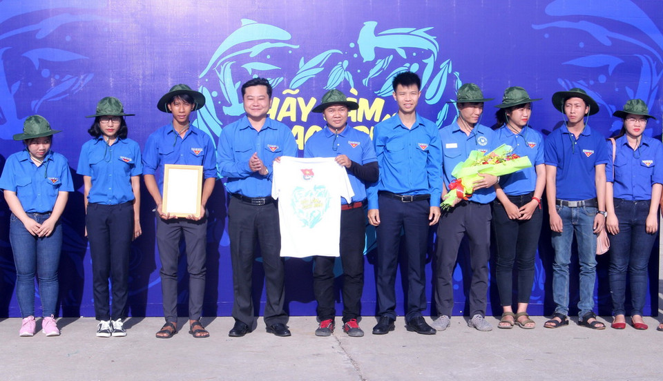 Đại diện Trung ương Đoàn Thanh niên Cộng sản Hồ Chí Minh tặng quà cho Đội Thanh niên tình nguyện làm sạch biển. (Ảnh: Hồng Hiếu/TTXVN)