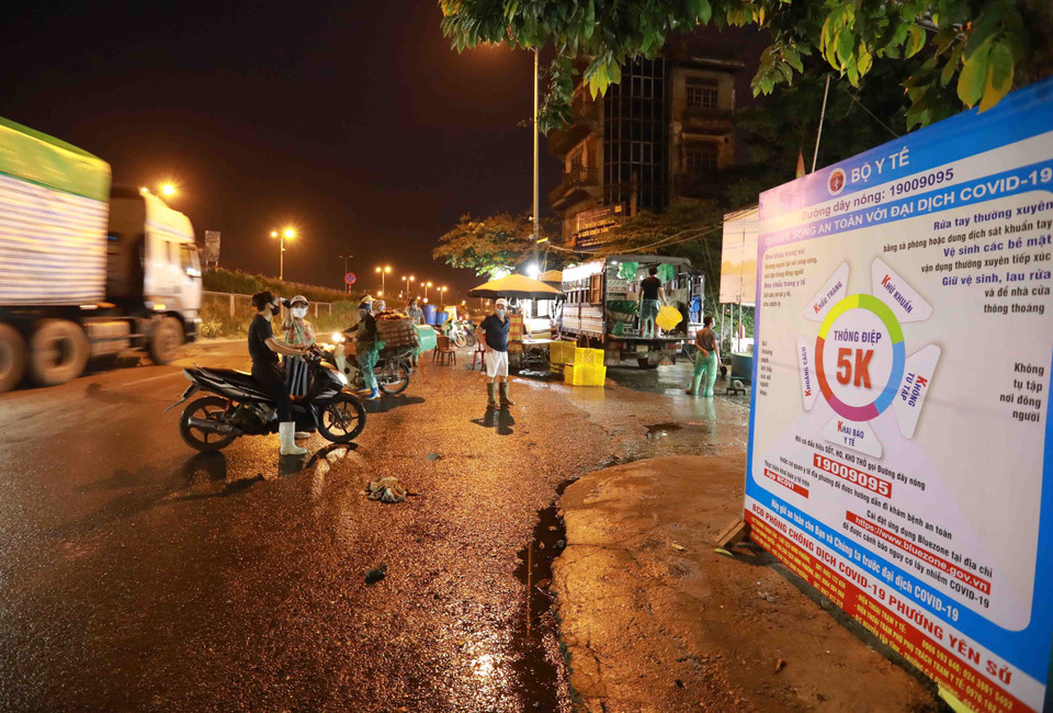 Ban quản lý chợ đo thân nhiệt cho tất cả người dân khi đến chợ để phòng, chống dịch. (Ảnh: Vũ Sinh/TTXVN)