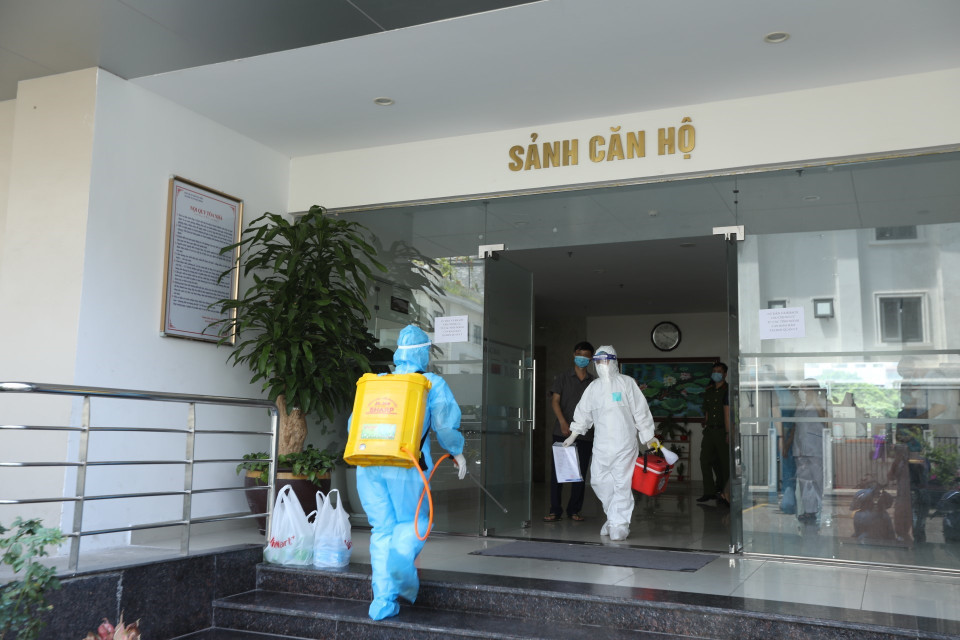 Nhân viên y tế phun khử khuẩn khu sảnh chung cư nơi bệnh nhân ở. (Ảnh: Minh Quyết/TTXVN)