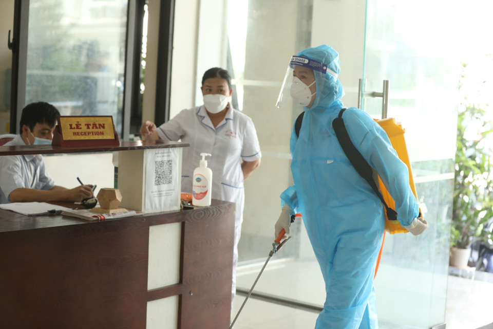 Nhân viên y tế phun khử khuẩn khu sảnh chung cư nơi bệnh nhân ở. (Ảnh: Minh Quyết/TTXVN)