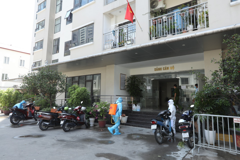 Nhân viên y tế phun khử khuẩn khu sảnh chung cư nơi bệnh nhân ở. (Ảnh: Minh Quyết/TTXVN)