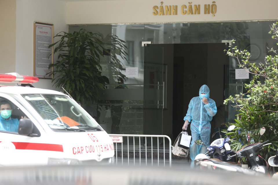 Đưa đi cách ly 2 trường hợp F1 liên quan đến bệnh nhân COVID-19 tại chung cư Thanh Xuân Building. (Ảnh: Minh Quyết/TTXVN)