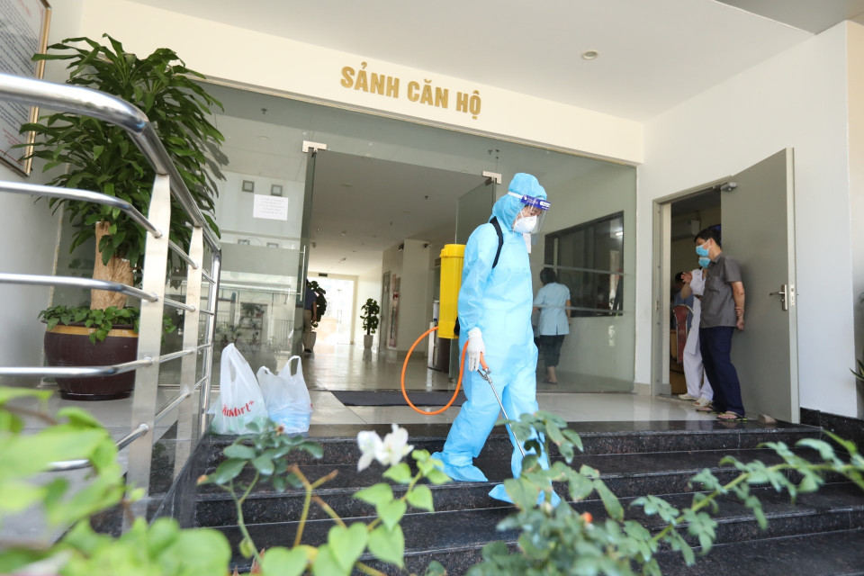Nhân viên y tế phun khử khuẩn khu sảnh chung cư nơi bệnh nhân ở. (Ảnh: Minh Quyết/TTXVN)