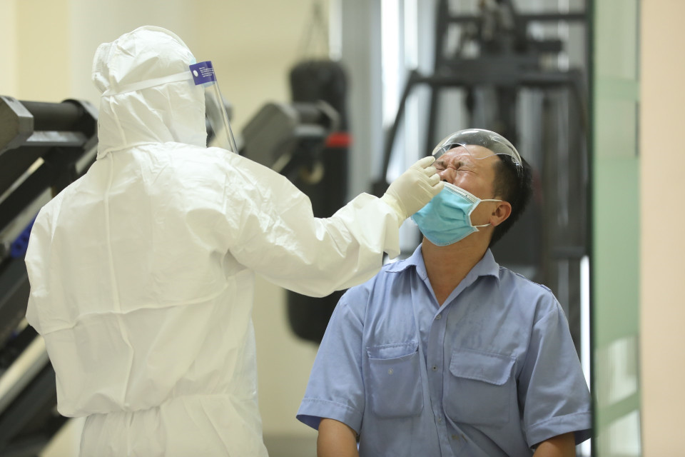 Nhân viên Trung tâm y tế quận Thanh Xuân đến lấy mẫu xét nghiệm cho những người liên quan. (Ảnh: Minh Quyết/TTXVN)