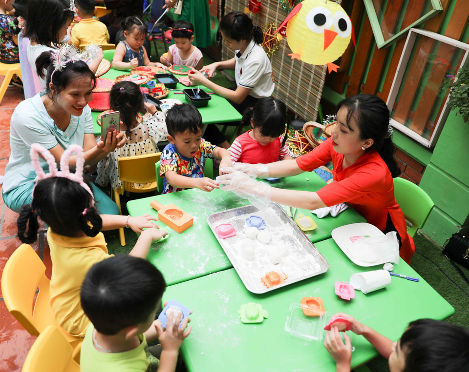 Các bé hào hứng với hoạt động trải nghiệm làm bánh, vẽ mặt nạ, vẽ nón, nặn tò he...trong dịp Tết Trung Thu. (Ảnh: Thanh Tùng/TTXVN)