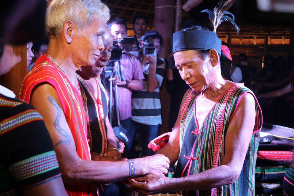 Chủ nhà trao vòng sức khỏe cho bạn sau lễ cúng. (Ảnh: Ngọc Minh/TTXVN)