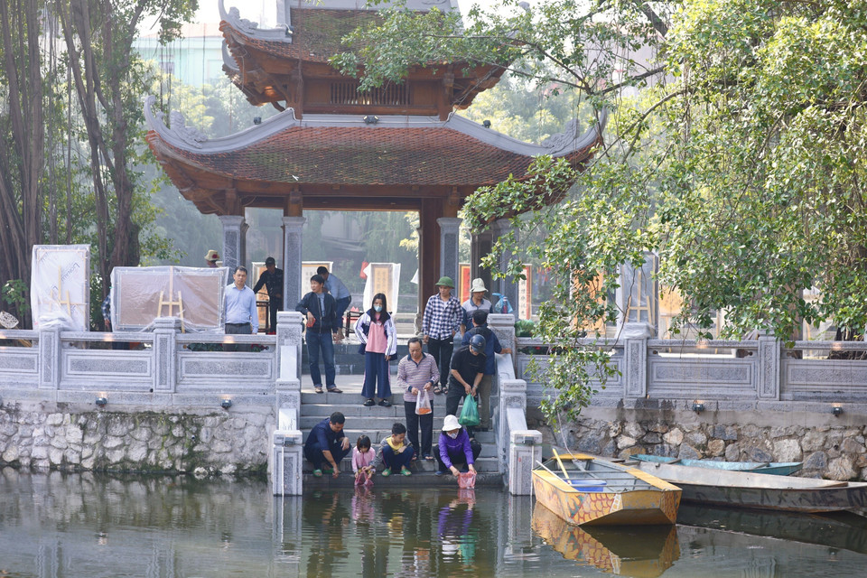 Người dân đi thả cá chép tại hồ Văn (Đống Đa, Hà Nội). (Ảnh: Hoàng Hiếu/TTXVN)