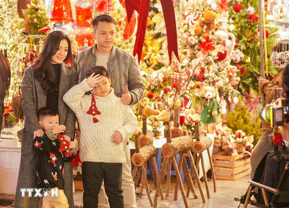 Một gia đình chọn phố Hàng Mã ngập tràn sắc Noel là địa điểm vui chơi ngày cuối tuần. (Ảnh: Khánh Hoà/TTXVN)