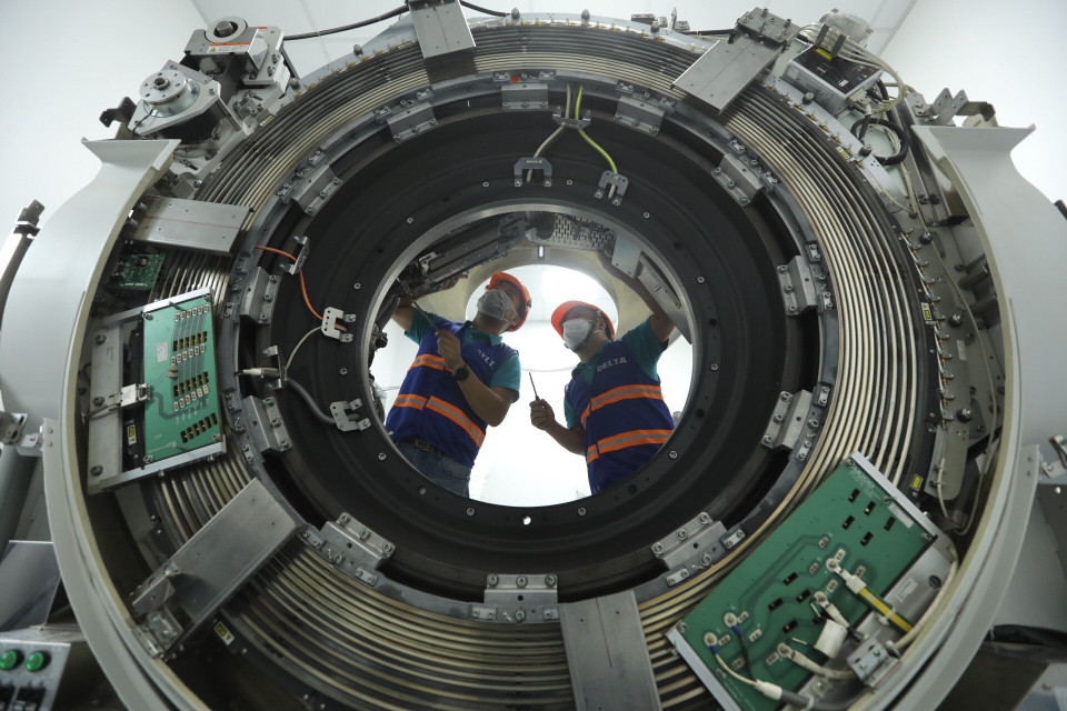 Nhân viên Công ty CP Thiết bị y tế Việt Nhật, đơn vị phối hợp với Bệnh viện Đại học Y Hà Nội hoàn thiện việc lắp đặt máy chụp cắt lớp vi tính tại bệnh viện dã chiến. (Ảnh: Minh Quyết/TTXVN)