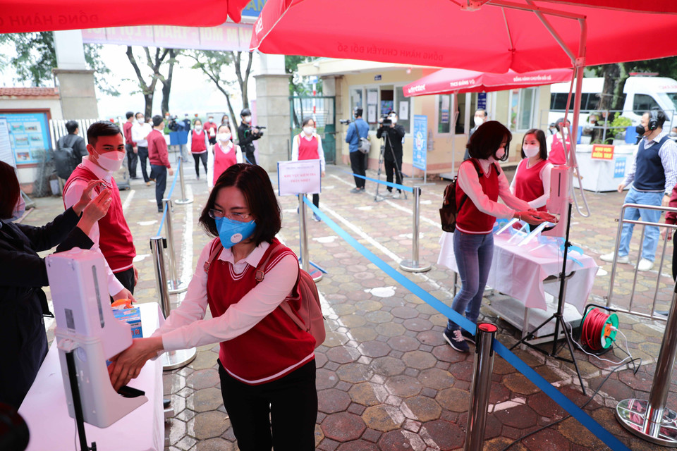 Hướng dẫn phân luồng, giãn cách, đo thân nhiệt và sát khuẩn tay khi học sinh tới trường. (Ảnh: Thanh Tùng/TTXVN)