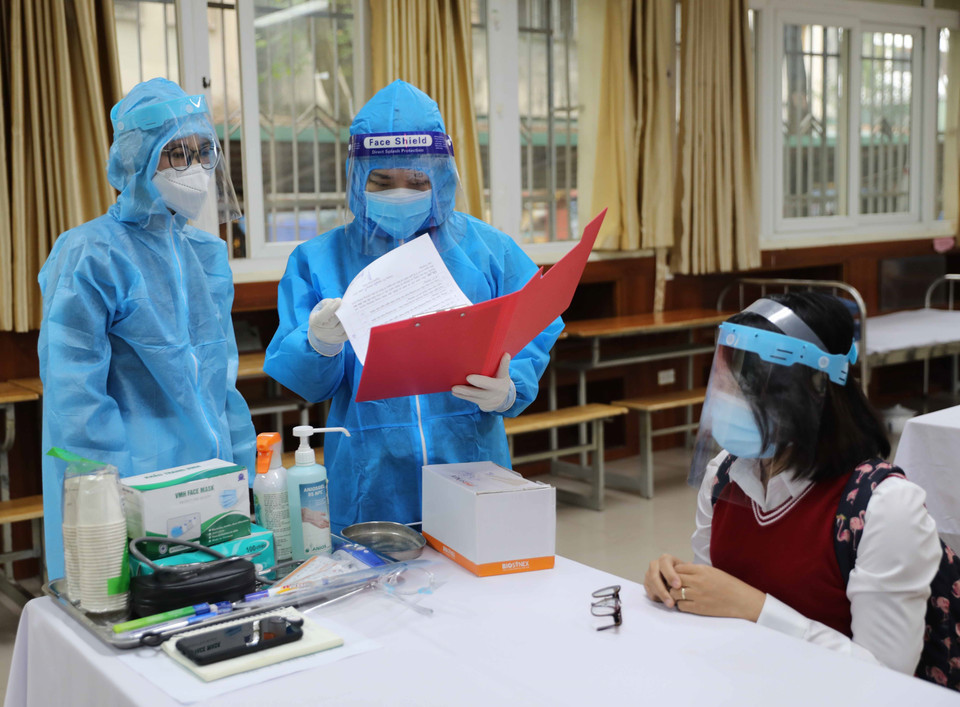 Nhân viên y tế phường xem hồ sơ của học sinh nghi mắc COVID-19. (Ảnh: Thanh Tùng/TTXVN)