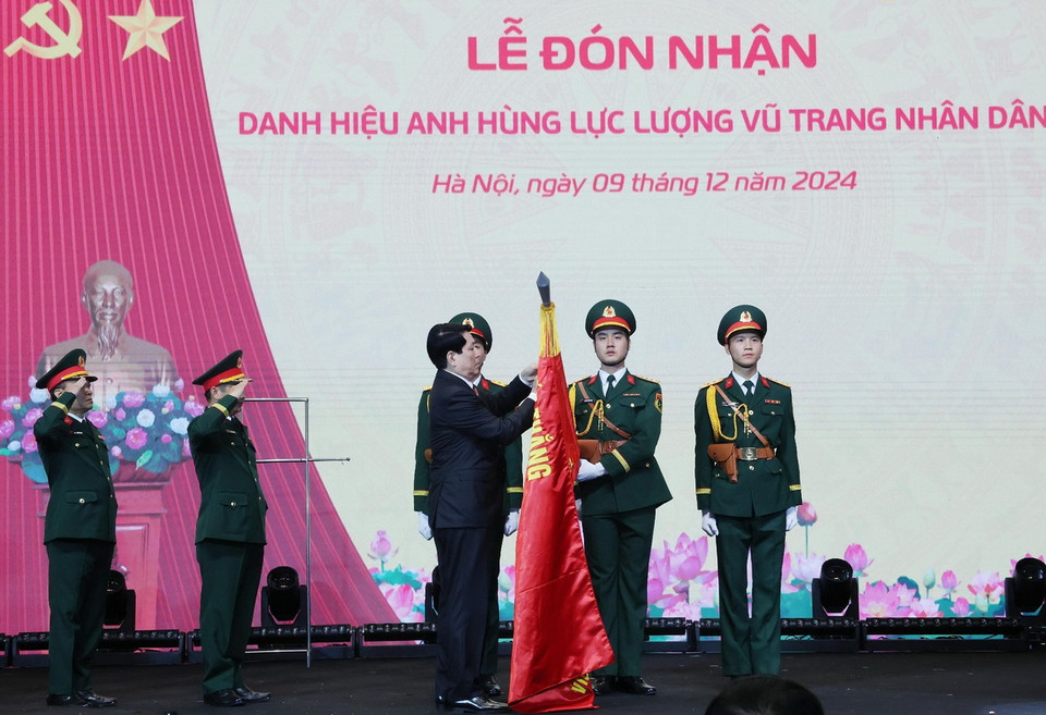Chủ tịch nước Lương Cường gắn huy hiệu Anh hùng Lực lượng vũ trang nhân dân lên lá cờ truyền thống Viện Hàng không Vũ trụ Viettel. (Ảnh: Lâm Khánh/TTXVN)
