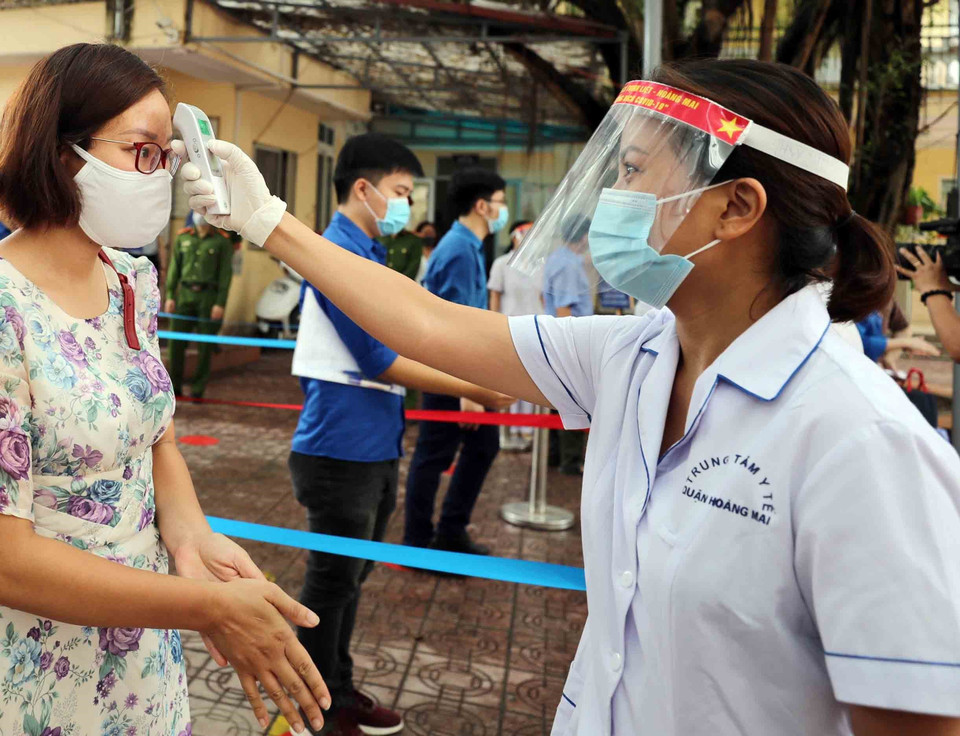 Cán bộ y tế sẽ hỗ trợ đo thân nhiệt cho thí sinh, cán bộ làm công tác thi khi tới điểm thi. (Ảnh: Thanh Tùng/TTXVN)