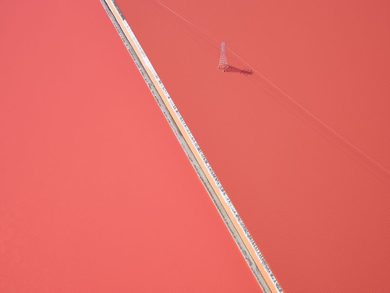 Đường dây điện cắt qua một đồng muối ở Bắc California. (Nguồn: NatGeo) Tùy thuộc vào thời tiết và thời gian của năm, một số vi khuẩn phát triển mạnh trong hồ khô, khiến đồng muối này chuyển sang màu hồng.