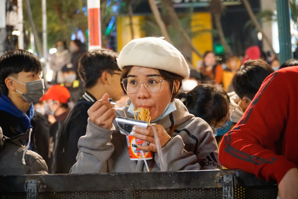 Có người còn tranh thủ ăn mỳ trong lúc chờ đợi chương trình ca nhạc. (Ảnh: Minh Hiếu/Vietnam+)