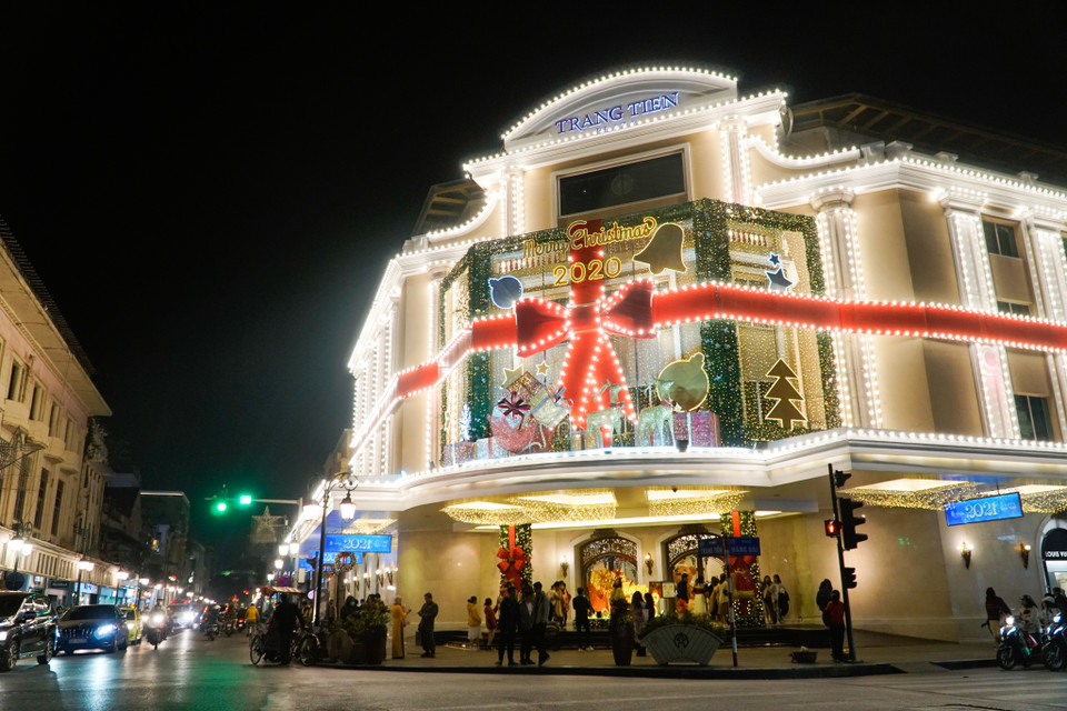 Khi phố lên đèn, Trung tâm thương mại Tràng Tiền Plaza nổi bật từ xa với hộp quà và chiếc nơ khổng lồ trang trí trước mặt tiền. (Ảnh: Minh Hiếu/Vietnam+)