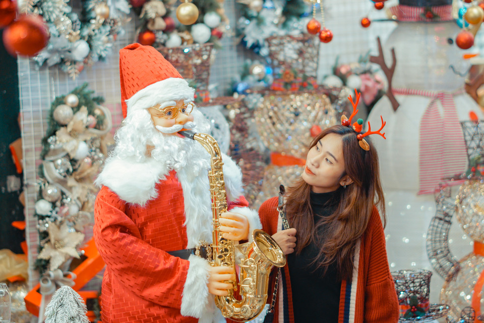 Một bạn nữ đang tạo dáng cùng với hình nộm ông già Noel. (Ảnh: Minh Hiếu/Vietnam+) 