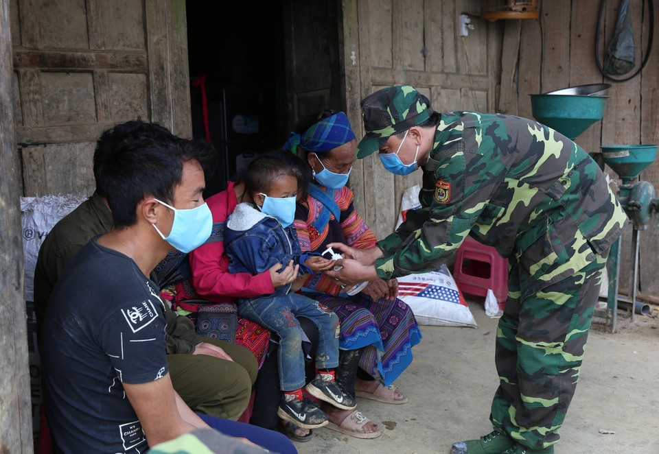 Cán bộ, chiến sỹ Đồn Biên phòng Pha Long, Bộ đội Biên phòng Lào Cai phát và hướng khử khuẩn phòng dịch cho người dân địa phương. (Ảnh: Dương Giang/TTXVN)