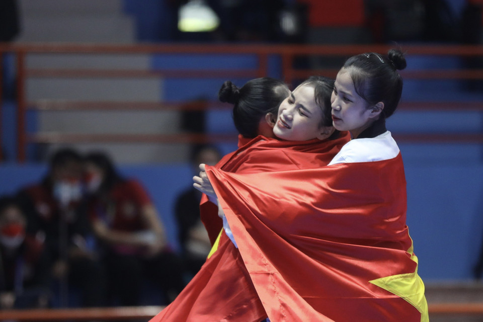 Khoảnh khắc mừng chiến thắng xúc động với lá cờ Tổ quốc trên mình của 3 vận động viên Nguyễn Thị Kim Hà, Ngô Thị Thùy Dung, Nguyễn Thị Hồng Trang khi giành huy chương vàng nội dung biểu diễn Quyền đồng đội nữ. (Ảnh: Minh Quyết/TTXVN)