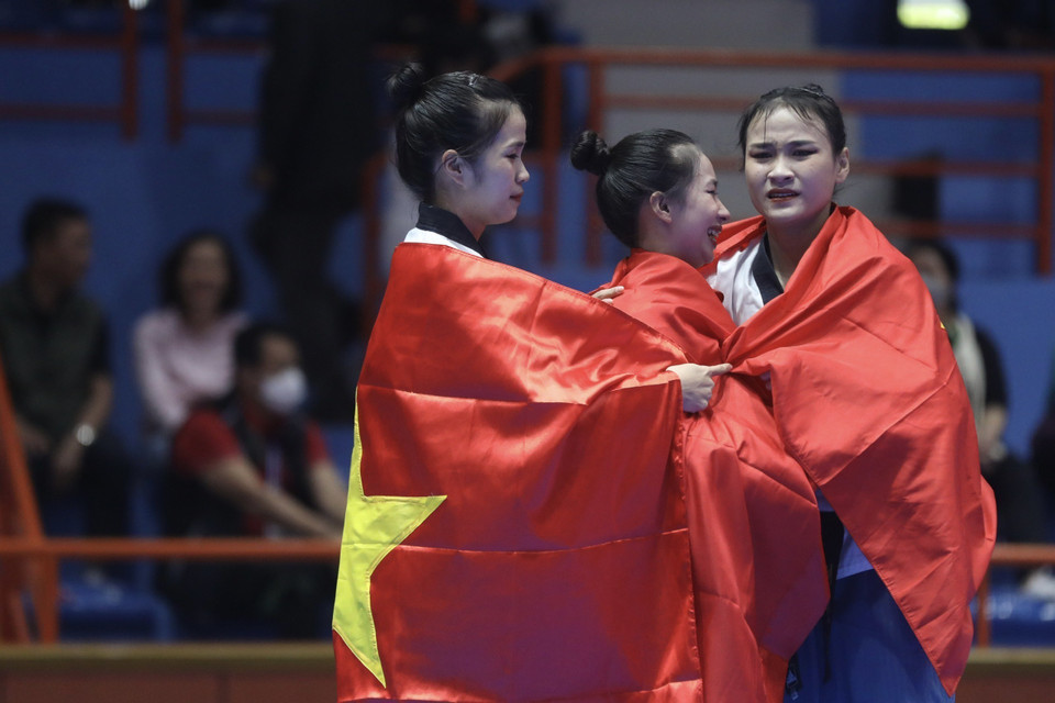 Khoảnh khắc mừng chiến thắng xúc động với lá cờ Tổ quốc trên mình của 3 vận động viên Nguyễn Thị Kim Hà, Ngô Thị Thùy Dung, Nguyễn Thị Hồng Trang khi giành huy chương vàng nội dung biểu diễn Quyền đồng đội nữ. (Ảnh: Minh Quyết/TTXVN)