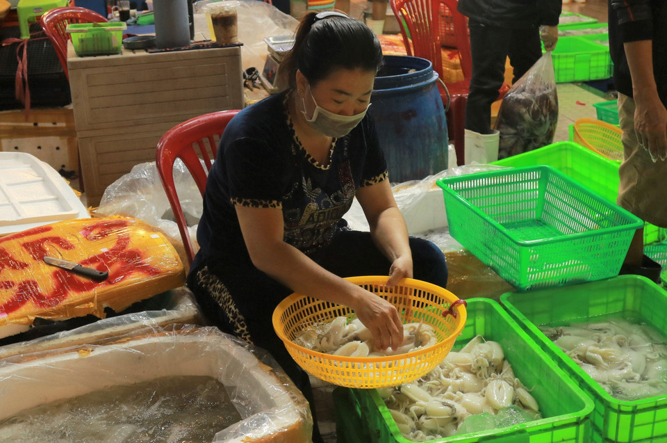 Tiểu thương phân loại hải sản tại khu vực buôn bán hải sản ở chợ đầu mối Bình Điền. (Ảnh: Anh Tuấn/TTXVN)