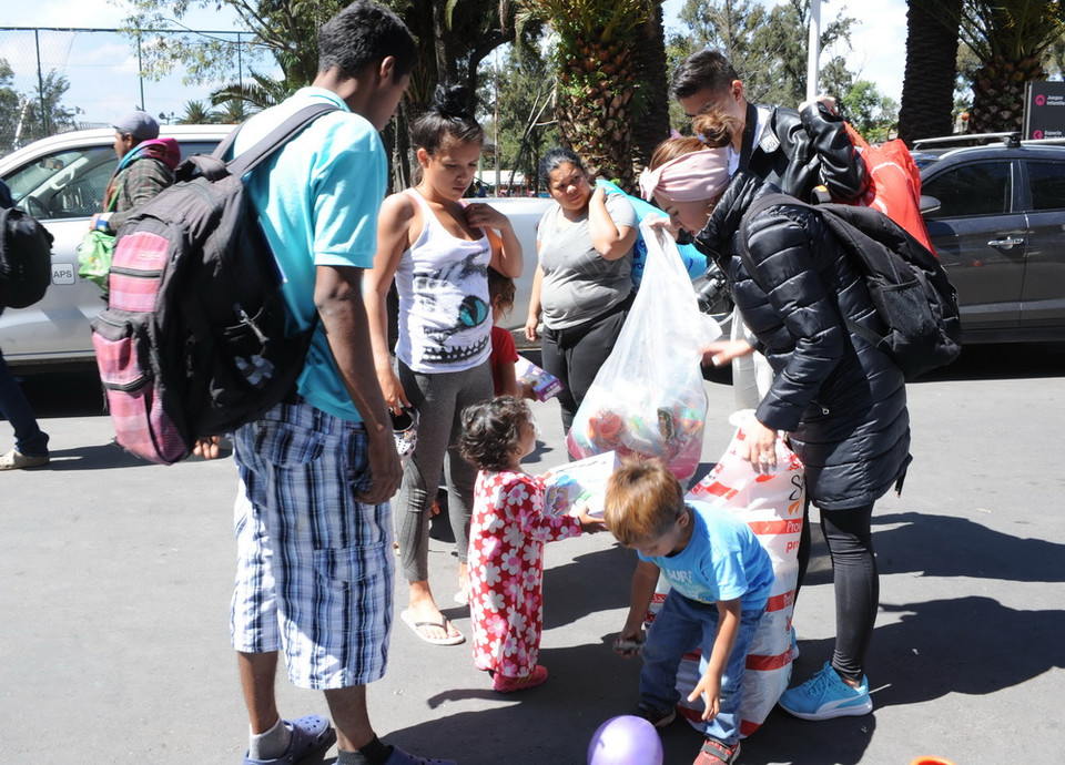 Một gia đình hỏa tâm trao những món quà cho các em bé người di cư. (Ảnh: Việt Hùng/Vietnam+)